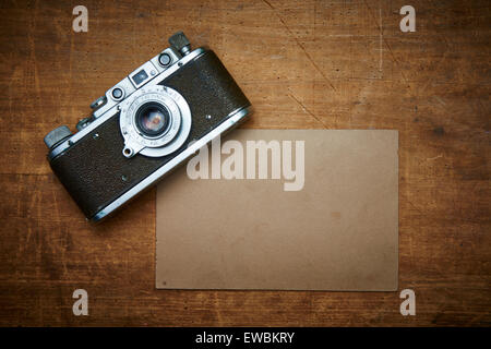 Vintage old retro film camera and old empty paper frame photos on wooden background. Nostalgic style picture, memories, Stock Photo