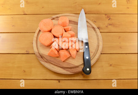 Pieces of chopped sweet potato with a sharp kitchen knife on a wooden chopping board Stock Photo