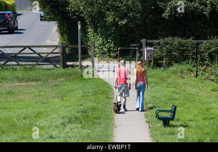 Rear view of a young couple walking a small dog on a sunny summer day Stock Photo