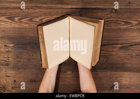 Woman hands holding blank old book on wooden planks Stock Photo