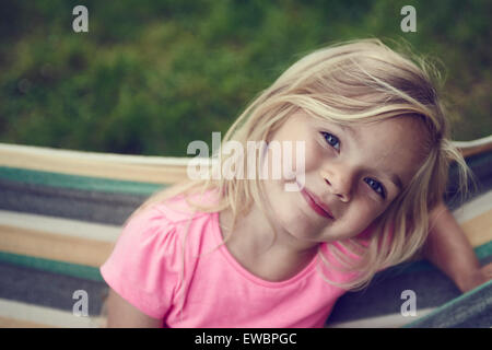 Child Blond Girl Lying in Hammock, summertime Stock Photo