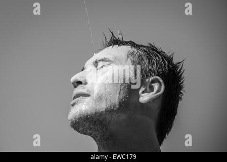 Photo of a man who's face is covered with water. Beautiful sky in the background. Stock Photo