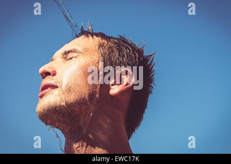 Photo of a man who's face is covered with water. Beautiful sky in the background. Stock Photo