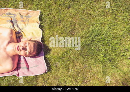 Photo of a young man that is sunbathing. A lot of greenery on the right side of the photo Stock Photo