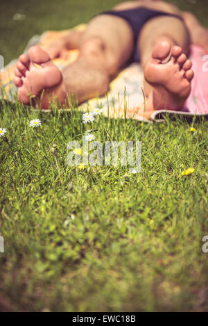Photo of a young man that is sunbathing. A lot of greenery in the foreground Stock Photo