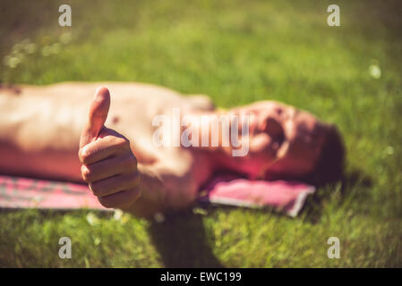 Photo of a young man that is sunbathing. A lot of greenery around Stock Photo