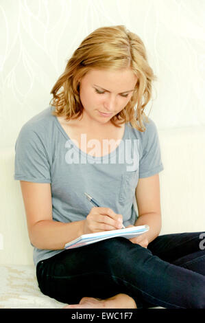 Young woman making notes in notebook Stock Photo