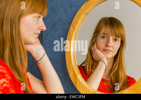 Caucasian redhead teenage girl looking in mirror Stock Photo