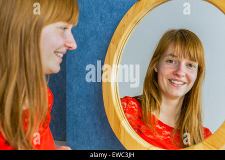Portrait of caucasian redhead teenage girl looking in mirror Stock Photo