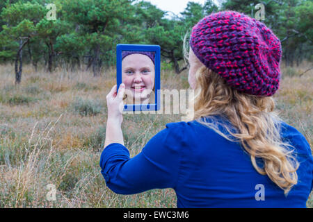 Dutch teenage girl holding mirror in nature and looking at herself Stock Photo