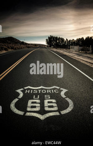 Classic image Historic Route 66 sign painted on highway. Dark and moody clouds, hazy sunshine Stock Photo