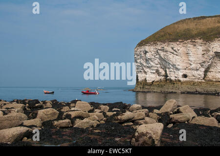 Blue sky & sea on sunny summer day & 2 different boats moored off-shore by towering chalk cliffs - North Landing, Flamborough, Yorkshire coast, GB UK. Stock Photo