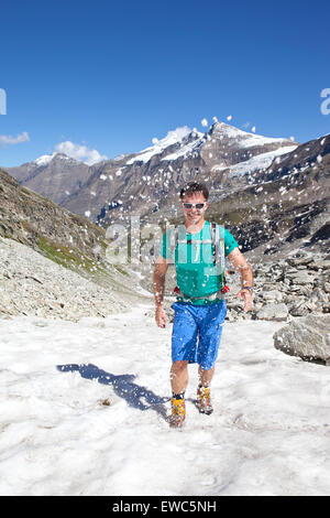A male hiker walking on snow in a t-shirt, during the Glocknerrunde, a 7 stage trekking from Kaprun to Kals around the Stock Photo