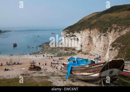 Old wooden fishing boat, chalk cliffs, people on the sunny summer sand & blue sky & sea - North Landing beach, Flamborough, Yorkshire, England, UK. Stock Photo