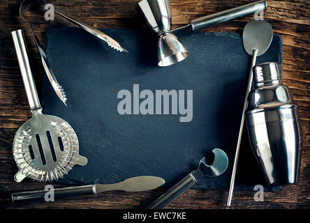 Set of bar accessories for making a cocktails arranged on a wooden background with black board for copy space Stock Photo