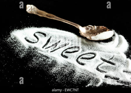 Word 'sweet' written in sugar on a black background. Stock Photo