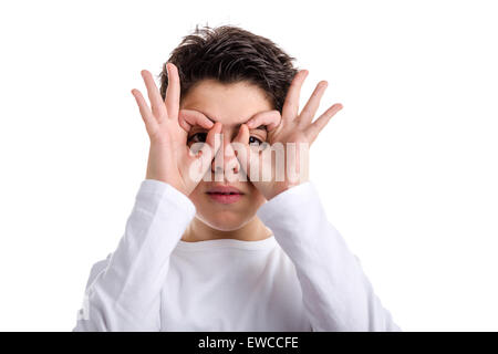 Happy Caucasian boy with acne skin in a white long sleeve t-shirt is making fan placing his hands on face as a mask Stock Photo