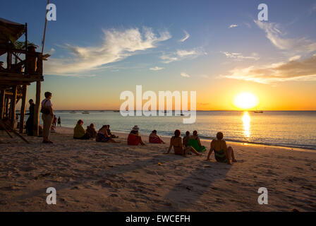 Tourists watch the sunset on Nungwi Beach, Zanzibar, Tanzania. Stock Photo