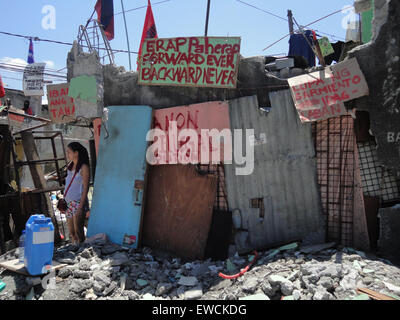 Manila, Philippines. 23rd June, 2015. A resident of Sarmiento Street stands beside placards protesting the demolition of their homes. Residents demanded the local government of Manila to halt the planned demolition of their homes, alleging that the projects planned for the place are alibis to accommodate a bus company owned by Guia Gomez, one of the many mistresses of Manila mayor Joseph Estrada. Credit:  Richard James Mendoza/Pacific Press/Alamy Live News Stock Photo