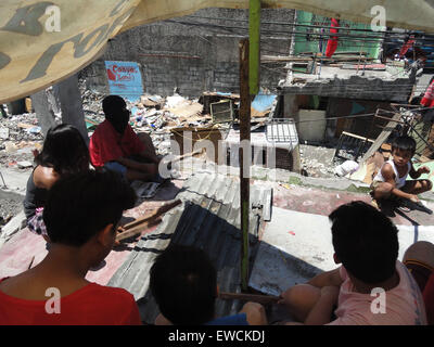 Manila, Philippines. 23rd June, 2015. Residents of Sarmiento Street, whose homes were demolished last June 16, perform a noise barrage by banging at a corrugated roof tile to protest the demolition of their homes. Residents demanded the local government of Manila to halt the planned demolition of their homes, alleging that the projects planned for the place are alibis to accommodate a bus company owned by Guia Gomez, one of the many mistresses of Manila mayor Joseph Estrada. Credit:  Richard James Mendoza/Pacific Press/Alamy Live News Stock Photo