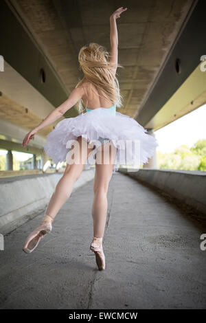 Graceful ballerina doing dance exercises on a concrete bridge Stock Photo