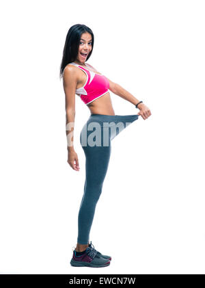 Full length portrait of a cheerful sporty woman showing big pants isolated on a white background Stock Photo