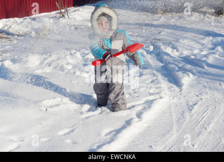 warmly dressed in overalls boy playing outdoors in snowy winter Stock Photo