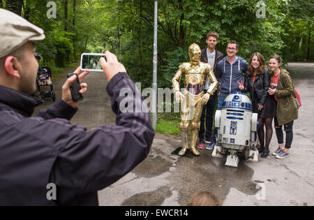Munich, Germany. 23rd June, 2015. Two wax figures in the shape of the gold humanoid protocol droid C-3PO (L) and the small astromech droid R2-D2 from the 'Star Wars' films stand in the Englisch Garden and are photographed with fans in Munich, Germany, 23 June 2015. Both figures are presented to the public during a promotional tour of Madame Tussaud's wax museum. Credit:  dpa picture alliance/Alamy Live News Stock Photo