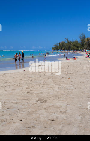 LUQUILLO BEACH, PUERTO RICO - MARCH 28, 2015: View sand and shore with people visible at Luquillo Beach in Puerto Rico. Stock Photo