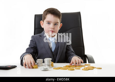 young small boy pretending he's working in an office counting chocolate money Stock Photo