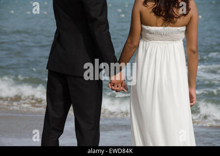 Lovers couple walking on beach wedding photo holding hands hugging laughing  Interracial couple Stock Photo