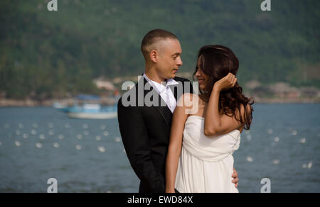 Lovers couple walking on beach wedding photo holding hands hugging laughing  Interracial couple Stock Photo