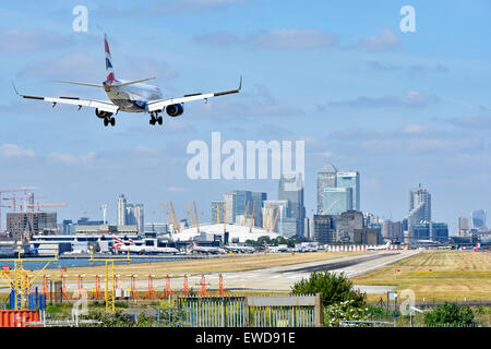 British Airways airplane landing London City Airport Newham with O2 arena & Canary Wharf in London Docklands skyline beyond Tower Hamlets England UK Stock Photo