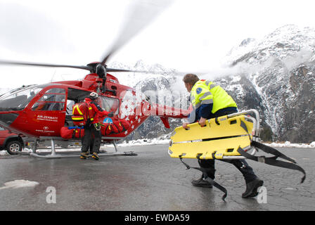 An ambulance paramedic is walking to a rescue helicopter to help an injured mountaineer that was flown down from a mountain Stock Photo