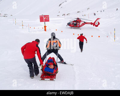 Rescue Personnel is helping an injured skier in the ski area of Zermatt in the Swiss Alps. Stock Photo