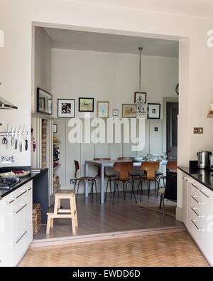 PK chairs around table in open plan kitchen dining area with parquet flooring Stock Photo