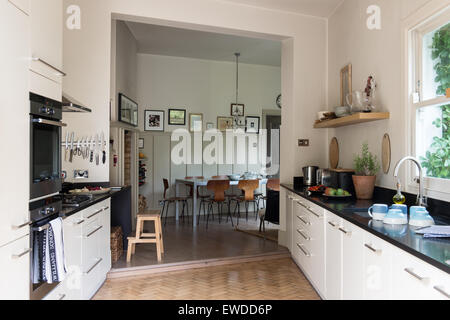 PK chairs around table in open plan kitchen dining area with parquet flooring and granite work surfaces Stock Photo