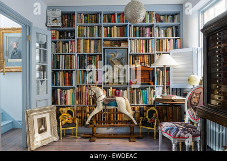 Blue painted shelves in library with antique rocking horse and Cory Visitorian upholstered chair