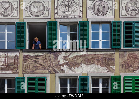 Young man leaning out of a window of a decorated house in the old town of Lucerne, Switzerland Stock Photo