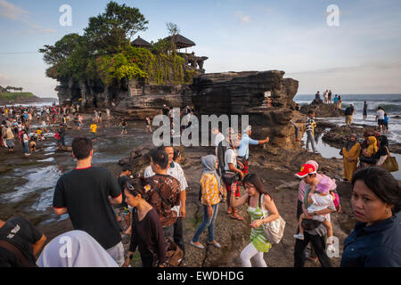 Tourists having leisure time on a rocky beach in Tanah Lot, Tabanan, Bali, Indonesia. Stock Photo