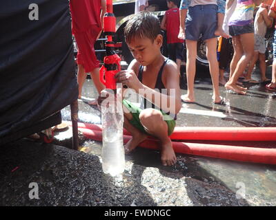 San Juan City, Philippines. June 24, 2015. A kid refilling his water gun during the annual Wattah! Wattah! Festival in San Juan, Metro Manila. The festival which is characterized by vigorous and boisterous street dancing with dousing of water is in honor of the town's patron saint: Saint John the Baptist. Credit:  Sherbien Dacalanio/Alamy Live News Stock Photo