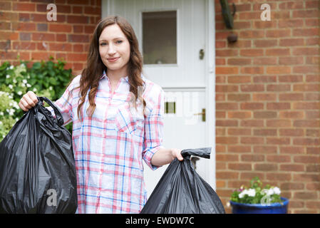 Portrait Of Woman Taking Out Garbage In Bags Stock Photo
