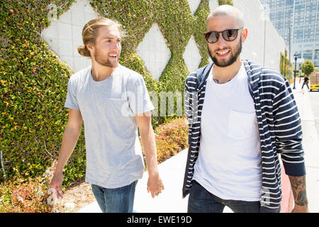 Two smiling young men walking in a park Stock Photo - Alamy
