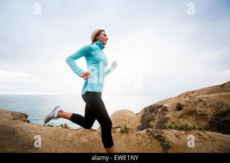 A young woman jogging along the coastal cliffs usa Stock Photo