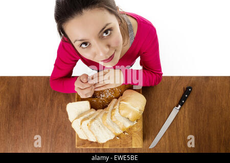 woman with a sliced up loaf of bread layed out on a wooden chopping board taken from a birds eye view from above looking down Stock Photo
