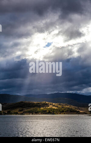 Sun Rays shining through clouds on the Hills of Lake Jindabyne, Australia Stock Photo