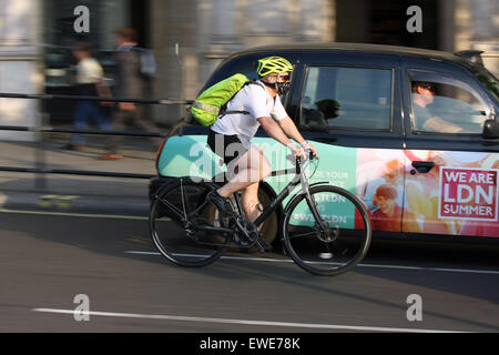 A cyclist and taxi traveling around Trafalgar Square, London, England Stock Photo