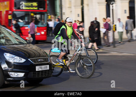 Two cyclists and a car traveling around Trafalgar Square in London, England Stock Photo