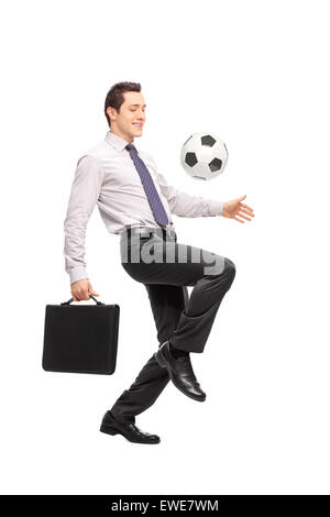 Full length portrait of a young businessman holding a briefcase and juggling a football isolated on white background Stock Photo