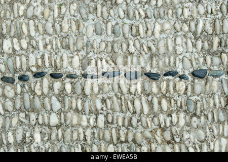 Pebbles in concrete pathway pattern Stock Photo